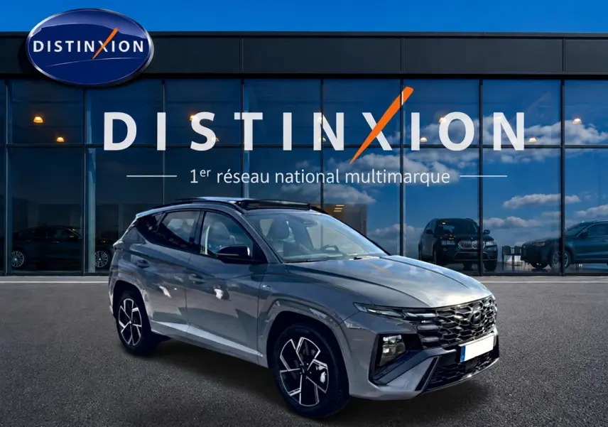 Hyundai Tucson gris shadow en 3/4 avant droit, avec jantes alu et toit panoramique en verre visible.