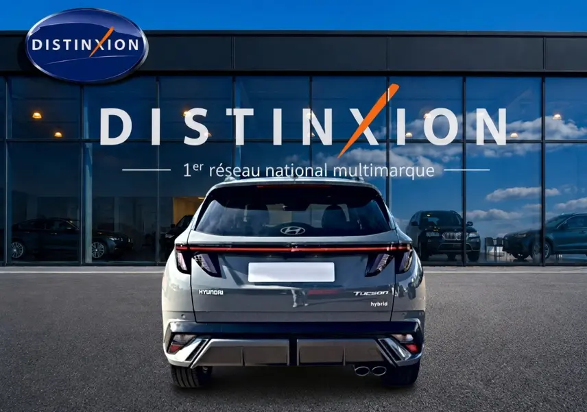 Vue arrière d'un Hyundai Tucson gris shadow hybride, avec feux arrière LED et double sortie d'échappement visible.