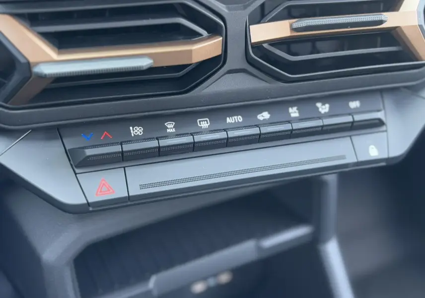 Gros plan sur la console centrale du Dacia Duster 2025 noir nacré, mettant en valeur les commandes de climatisation et les aérateurs.