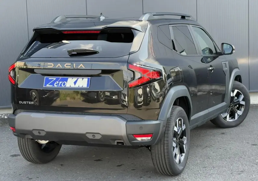 Vue 3/4 arrière droite d'un Dacia Duster noir nacré avec barres de toit et jantes alliage 17 pouces.
