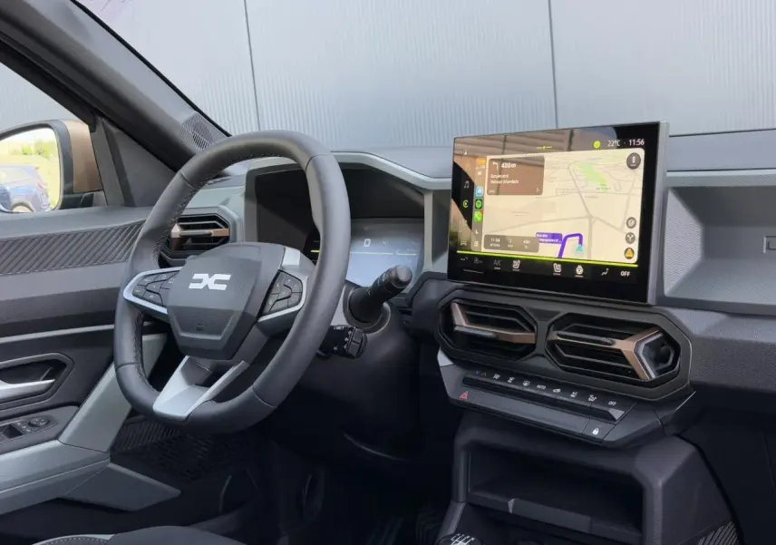 Intérieur du Dacia Duster 2025, vue côté conducteur sur volant, écran tactile GPS et aérateurs hexagonaux.