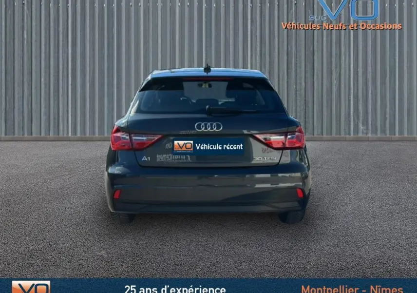 Vue arrière d'une Audi A1 Sportback gris foncé 2020 avec feux arrière allumés et radar de stationnement visible.