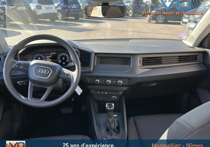 Vue intérieure avant de l'Audi A1 Sportback 30 TFSI 2020 avec tableau de bord gris et console centrale équipée d'une boîte automatique.