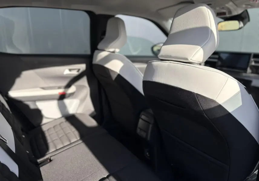 Vue intérieure côté gauche montrant les sièges arrière et avant en tissu gris clair et noir du Citroën C3 Aircross Hybrid 2025.