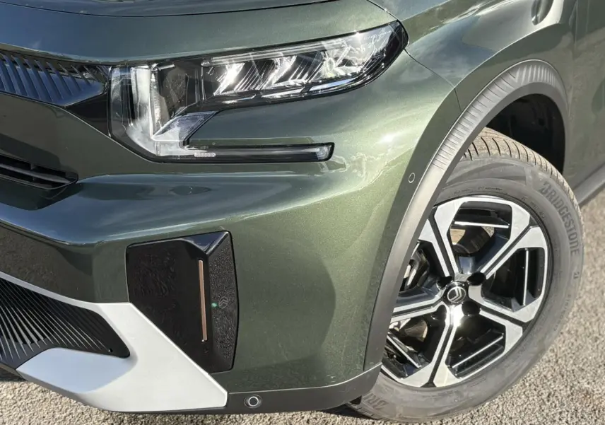 Gros plan sur l'avant droit du Citroën C3 Aircross 2025 en Vert Montana avec jante alliage et phares LED distinctifs.