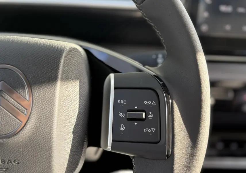 Gros plan sur les commandes multifonctions à droite du volant du Citroën C3 Aircross Hybrid 145, cuir noir.
