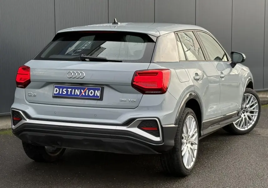 Audi Q2 35 TDI S-Line gris Flèche vue 3/4 arrière droit, avec feux LED et jantes alliage distinctives.