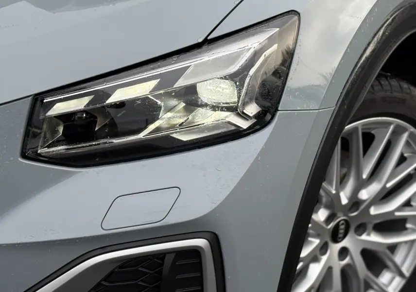 Gros plan sur le phare avant droit et la roue alliage de l'Audi Q2 35 TDI S-Line en Gris Flèche.