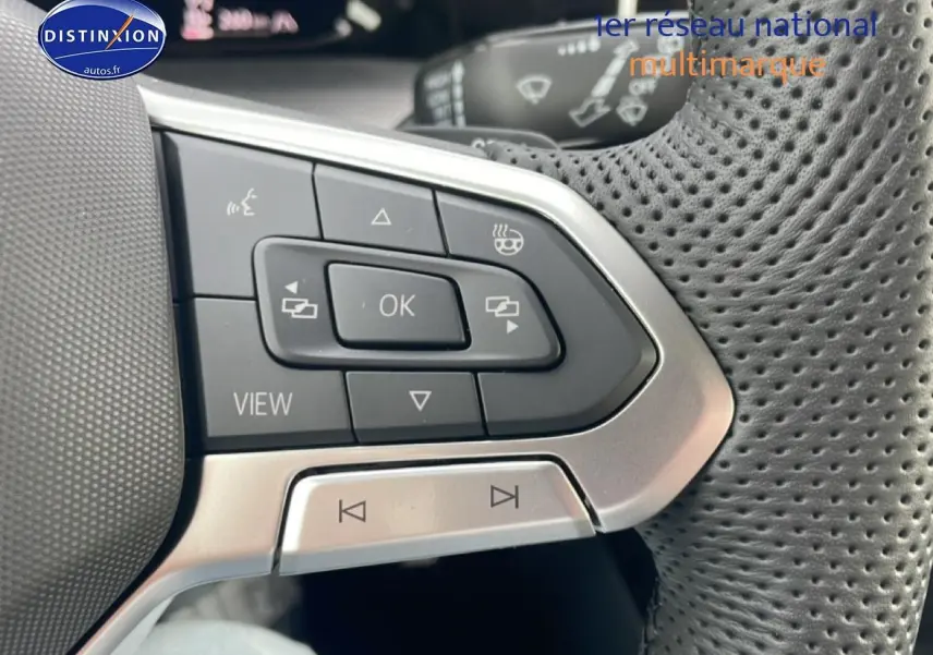 Gros plan sur les commandes multifonctions à gauche du volant cuir perforé d’une Volkswagen Golf noire 2026.