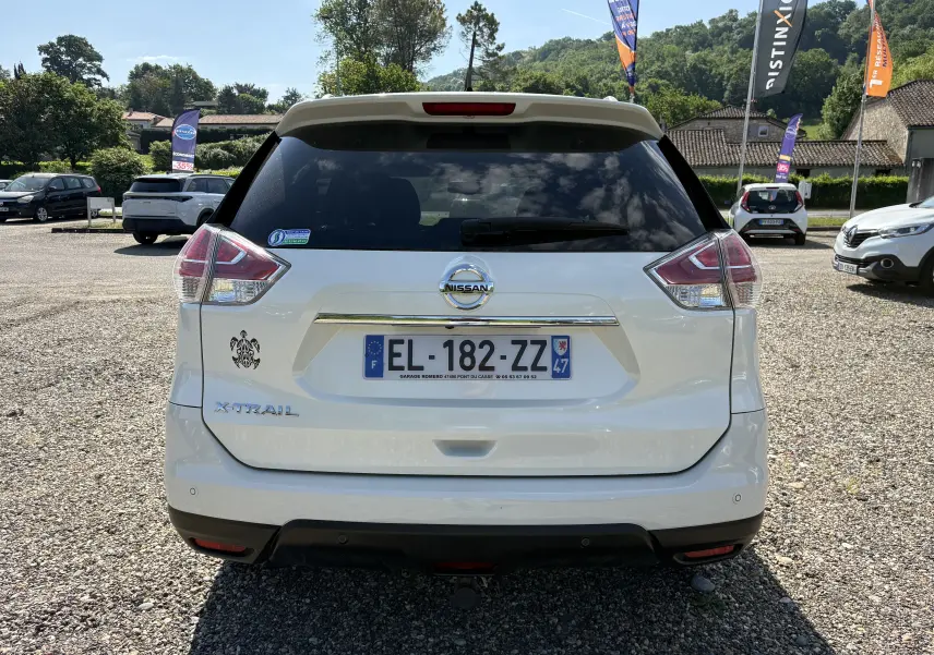 Vue de profil côté gauche d'un Nissan X-TRAIL 2016 blanc, version White Edition 7 places avec jantes alliage noires et argentées.