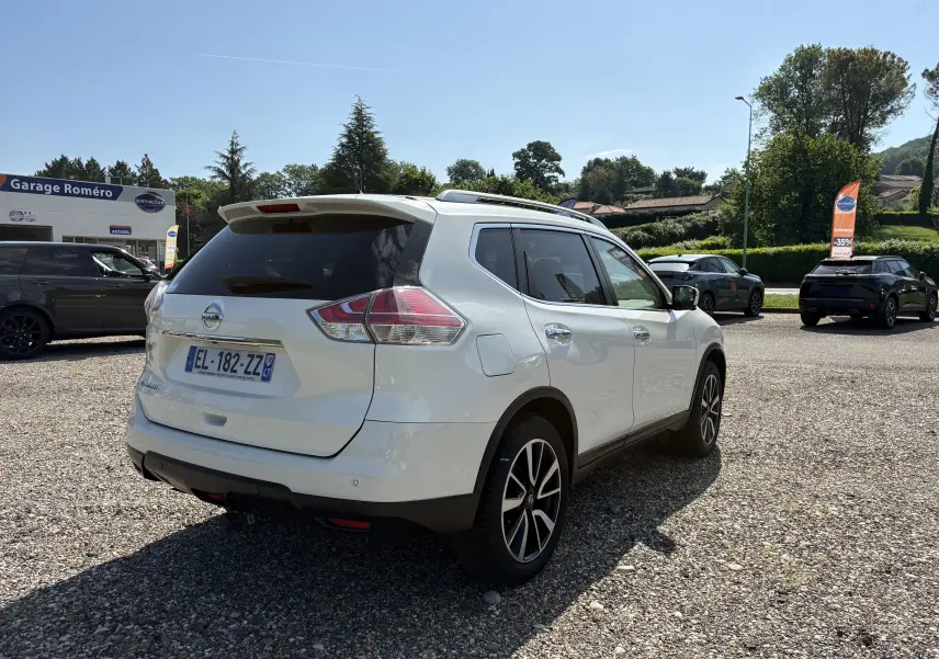 Vue arrière d'un Nissan X-TRAIL blanc 2016 avec logo X-TRAIL et plaque d'immatriculation française visible.