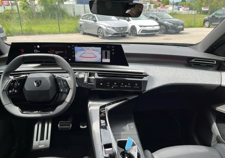 Vue intérieure avant du Peugeot 5008 Hybrid gris artense, volant multifonctions et écran tactile central avec caméra de recul.