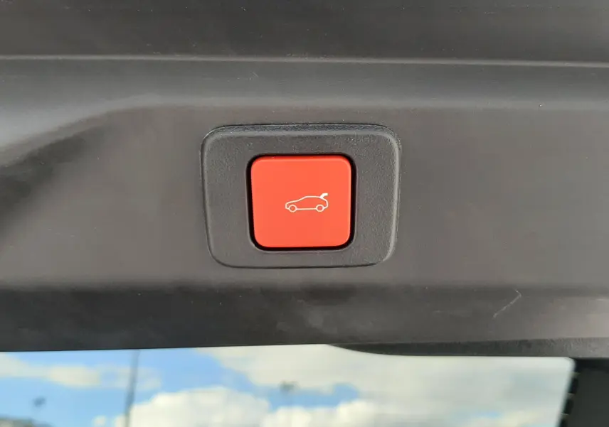 Bouton rouge de fermeture électrique du hayon visible sur l'intérieur arrière d'un Peugeot 3008 gris titane.