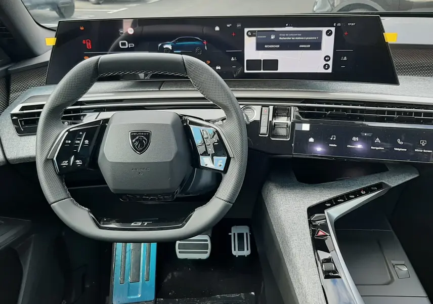 Vue intérieure avant du poste de conduite du Peugeot 3008 gris titane 2026, avec volant compact et double écran numérique panoramique.