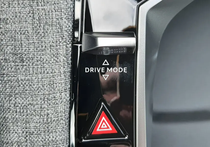 Gros plan sur le bouton Drive Mode et le triangle de signalisation rouge sur la console noire intérieure du Peugeot 3008 gris titane.