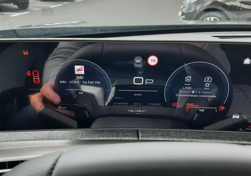 Vue rapprochée du tableau de bord numérique du Peugeot 3008 gris titane, affichant la vitesse et la consommation instantanée.