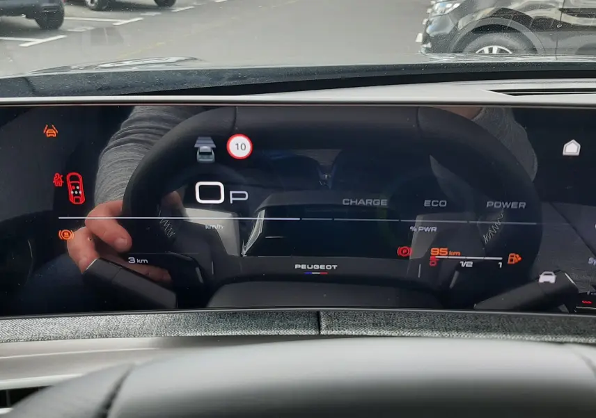 Vue intérieure du tableau de bord numérique du Peugeot 3008 gris titane, affichant les indicateurs de charge et vitesse.