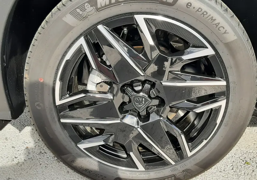 Gros plan sur la roue avant gauche du Peugeot 3008 gris titane, jante alliage noire et pneus Michelin e-Primacy.