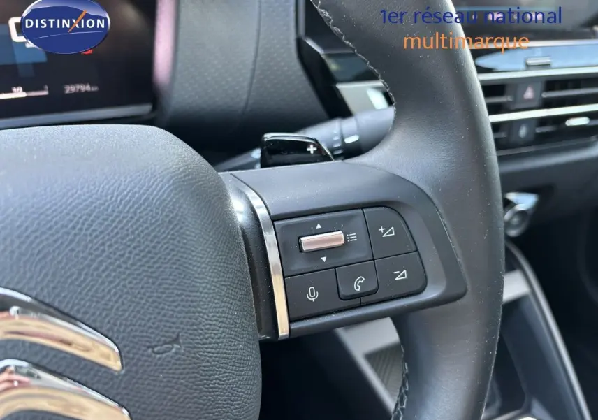 Gros plan sur le volant avec commandes intégrées du Citroën C4 gris Artense, version essence 2022, intérieur moderne.