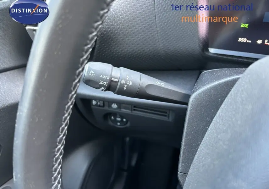 Gros plan sur la commande des feux et clignotants côté gauche du volant dans l'habitacle d'une Citroën C4 gris Artense 2022.