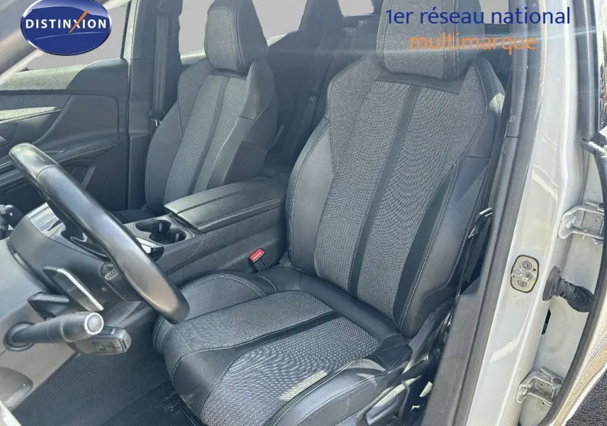 Vue intérieure côté conducteur du Peugeot 3008 blanc nacré 2022, mettant en valeur les sièges en tissu et cuir noir.