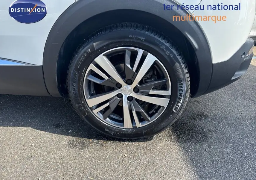 Gros plan sur la roue arrière droite du Peugeot 3008 blanc nacré, mettant en valeur la jante alliage 18 pouces et le pneu Michelin.