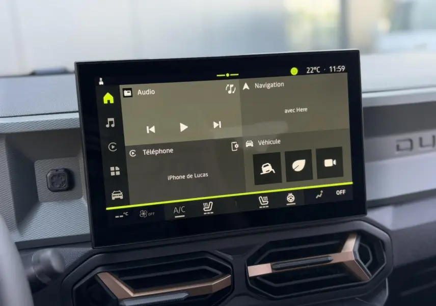 Écran tactile 10 pouces du tableau de bord du Dacia Duster 2025, avec interface multimédia et commandes climatisation visibles.