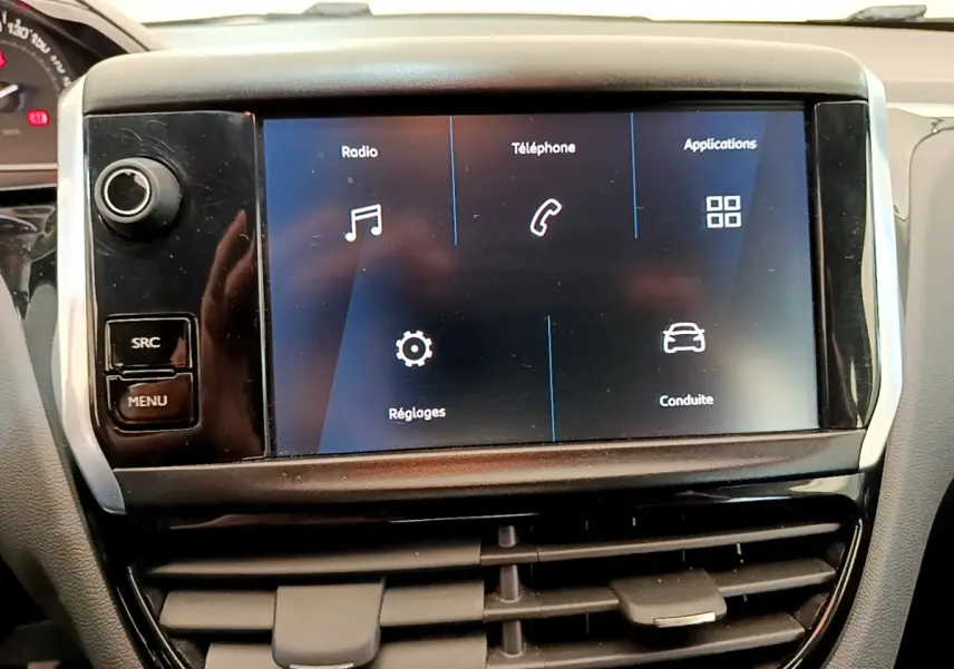Écran tactile central affichant les options radio, téléphone et applications dans l'habitacle d'une Peugeot 208 blanche.