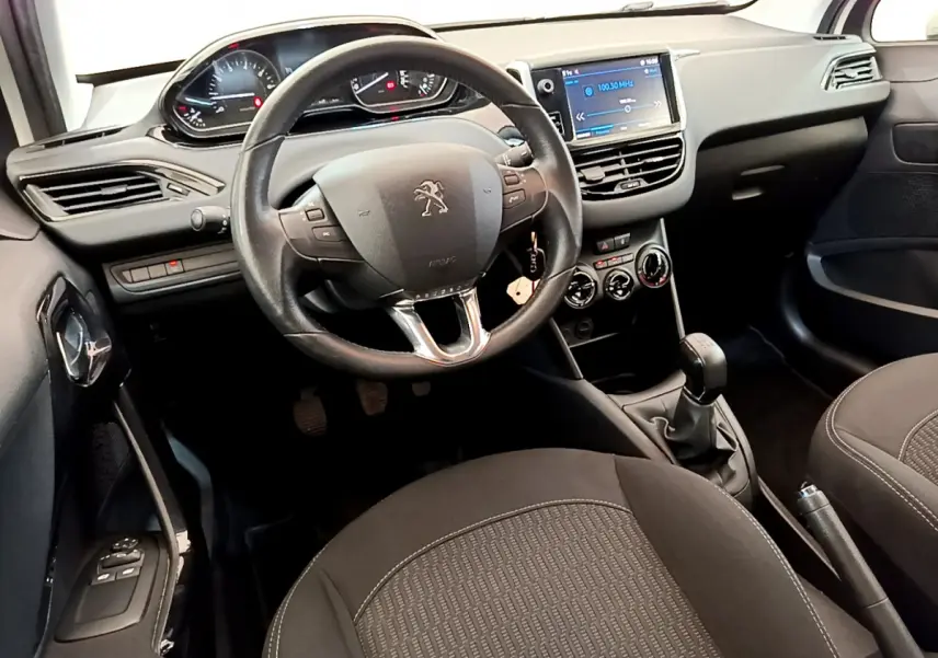Intérieur de la Peugeot 208 Puretech 82 Signature 2019, vue côté conducteur sur le tableau de bord et volant cuir noir.