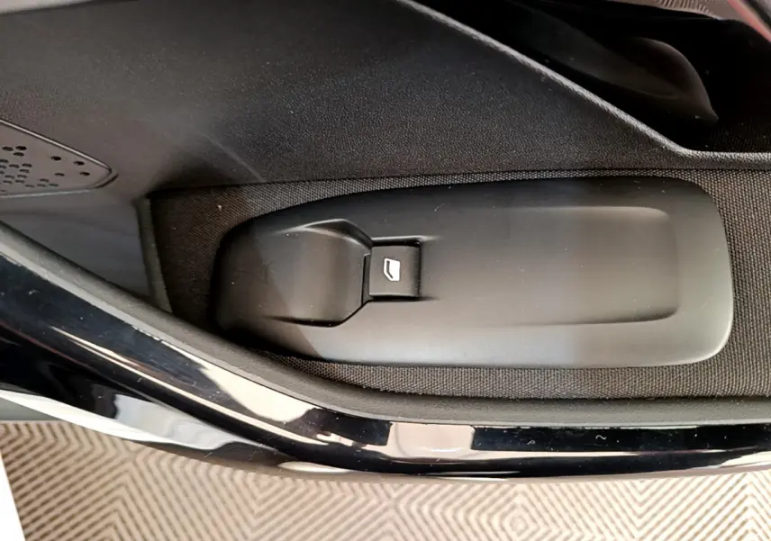 Bouton de commande de lève-vitre électrique sur la porte intérieure d'une Peugeot 208 blanche Puretech 82 Signature.