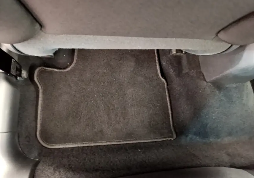 Plancher arrière avec tapis de sol noir sous la banquette d'une Peugeot 208 Puretech 82 Signature blanche de 2019.