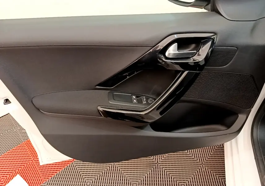 Gros plan sur la porte avant gauche noire avec poignée brillante d'une Peugeot 208 blanche de 2019.