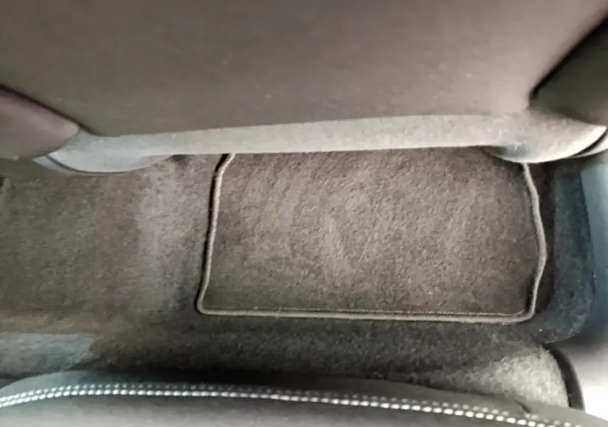 Vue rapprochée du tapis de sol gris foncé et de la base d'un siège avant sur Peugeot 208 Puretech 82 Signature blanc.