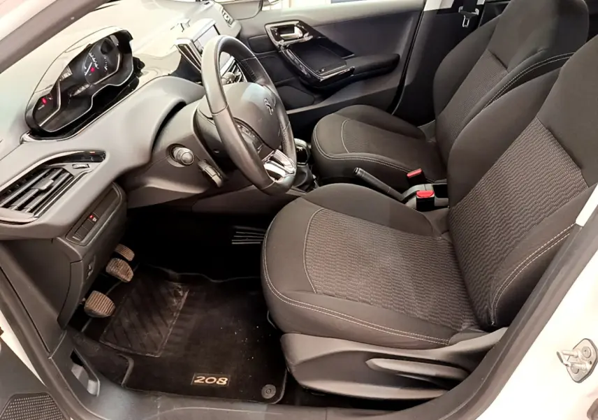 Intérieur avant droit de la Peugeot 208 Puretech 82 Signature 2019, sièges noirs et tableau de bord moderne.