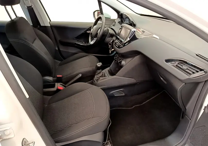 Intérieur noir de la Peugeot 208 Puretech 82 Signature 2019 vu côté passager, avec tableau de bord moderne et écran tactile.