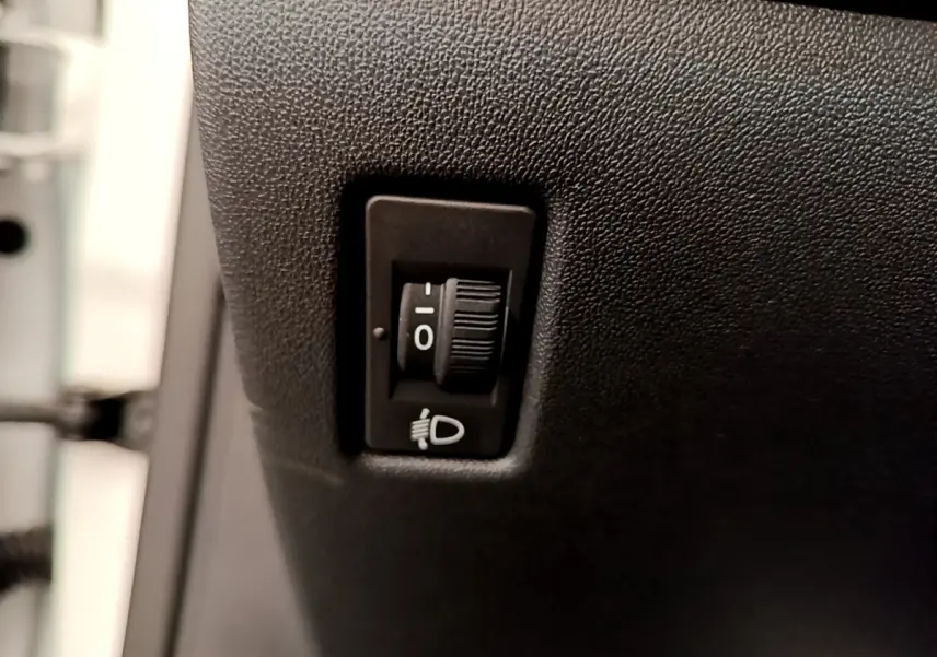 Molette de réglage des phares sur tableau de bord noir d'une Peugeot 208 Puretech 82 Signature blanche de 2019.