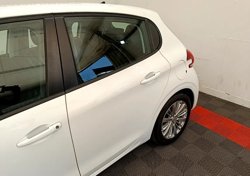 Vue latérale arrière droite d'une Peugeot 208 Puretech 82 Signature blanche avec jante alliage et poignée de porte blanche.