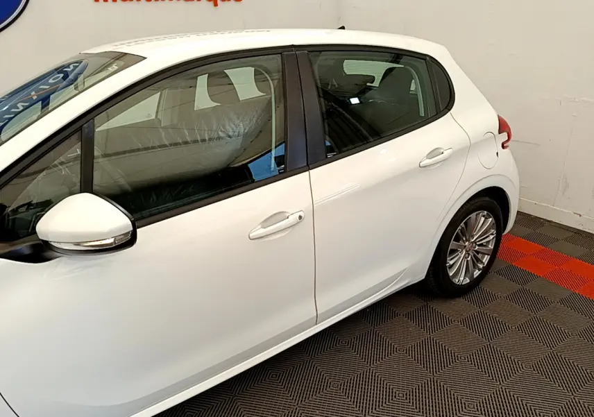Profil côté droit de la Peugeot 208 Puretech 82 Signature blanche, avec rétroviseurs chromés et jantes alliage visibles.