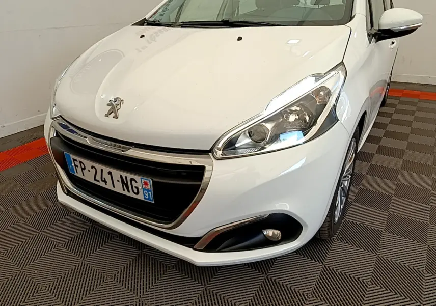 Peugeot 208 Puretech 82 Signature blanc vue 3/4 avant droit, avec phares et antibrouillards visibles.