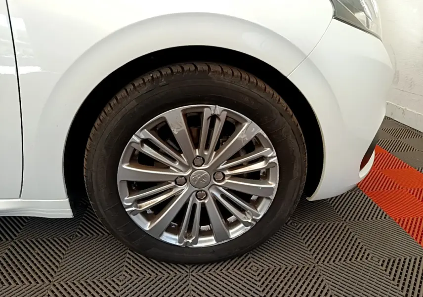 Gros plan sur la roue avant gauche de la Peugeot 208 Puretech 82 Signature blanche de 2019 avec jante alliage.