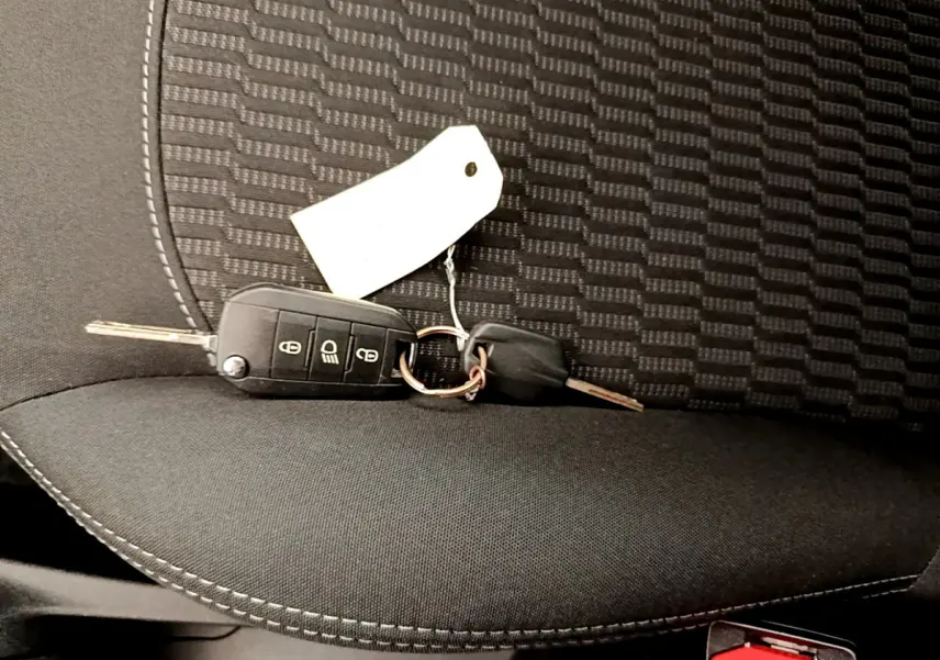 Clé de contact posée sur un siège tissu noir à motifs de la Peugeot 208 Puretech 82 Signature 2019.