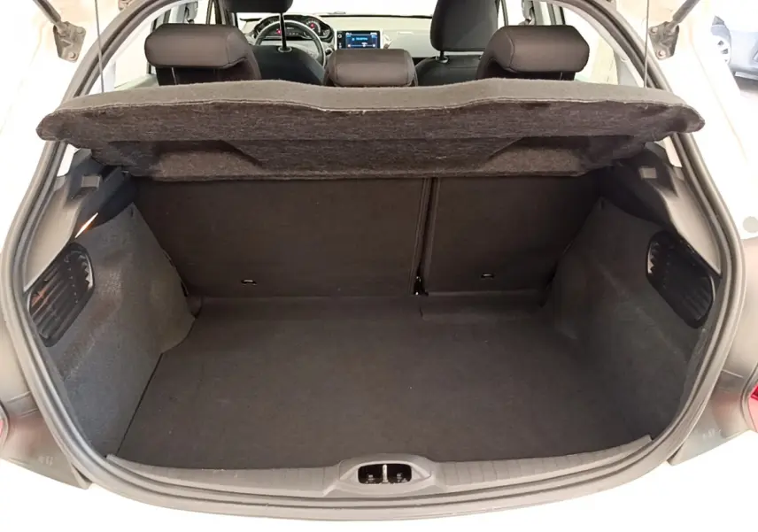 Coffre ouvert d'une Peugeot 208 blanche, vue arrière montrant l'espace de chargement et les sièges arrière.