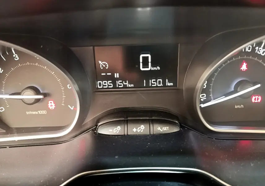 Tableau de bord de Peugeot 208 blanc, affichage numérique au centre avec compteur de vitesse à 0 km/h.