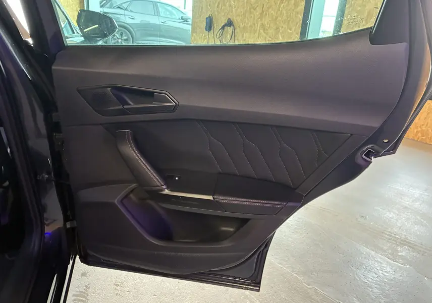 Vue intérieure de la porte arrière gauche noire du CUPRA Formentor 1.4 e-Hybrid 2023 avec surpiqûres décoratives.