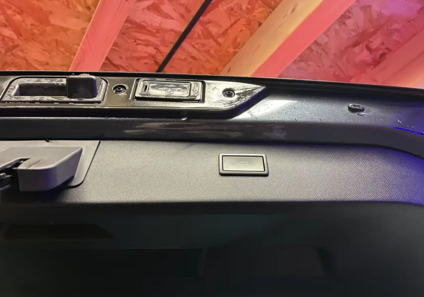 Bouton d'ouverture électrique du coffre sur la partie intérieure de la porte arrière d'un CUPRA Formentor gris.