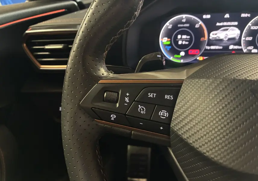 Gros plan sur le volant cuir perforé côté gauche du CUPRA Formentor gris, avec commandes de régulateur et tableau de bord numérique.