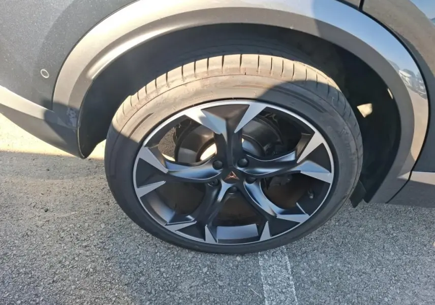 Gros plan sur la roue avant droite du CUPRA Formentor gris, mettant en valeur la jante noire et argentée au design sportif.