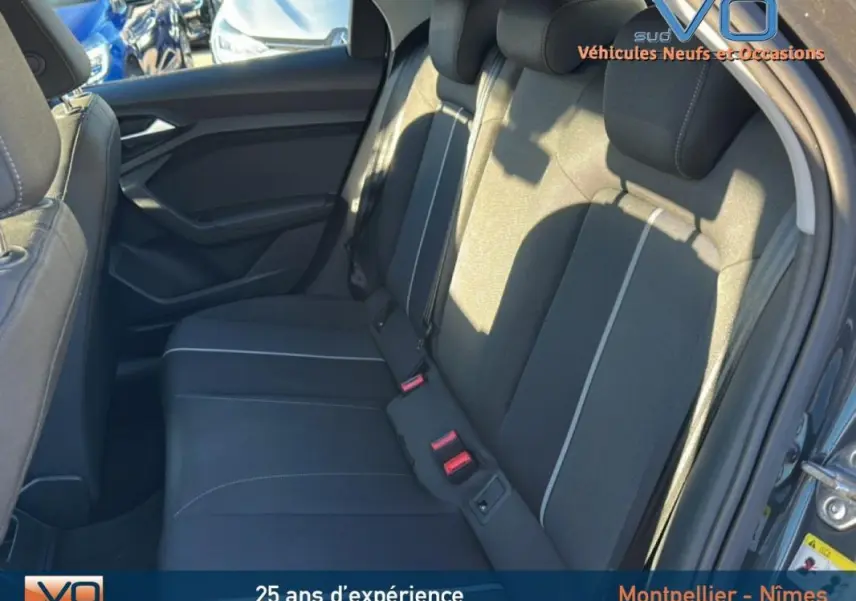 Vue intérieure des sièges arrière noirs avec surpiqûres claires de l'Audi A1 Sportback gris foncé, porte ouverte côté droit.