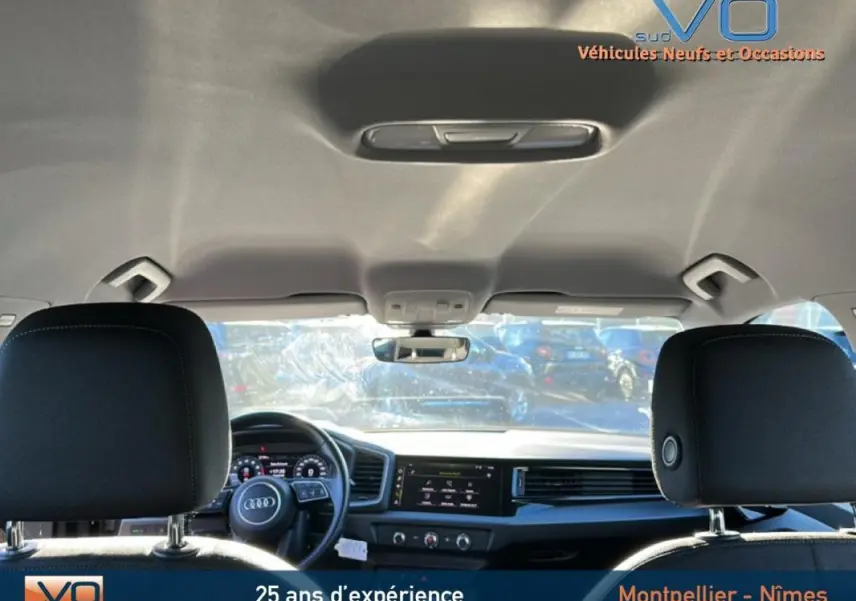 Vue intérieure arrière montrant le tableau de bord et le volant cuir d'une Audi A1 Sportback gris foncé de 2019.