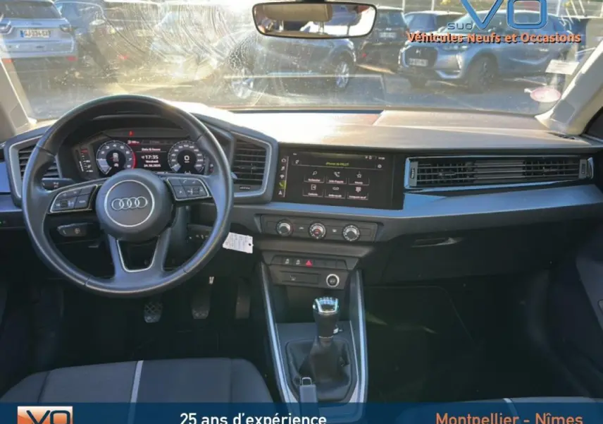Intérieur de l'Audi A1 Sportback 2019 vu de face, volant cuir, boîte manuelle, écran tactile et cockpit numérique visibles.